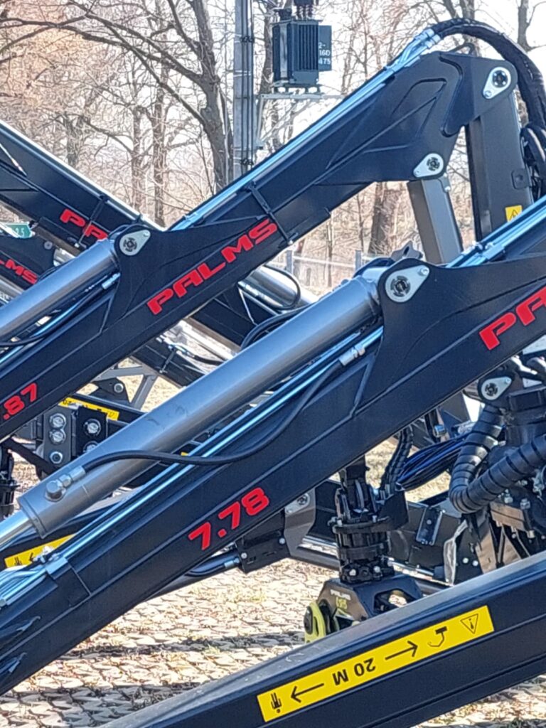 Ramiona żurawi hydraulicznych PALMS model 7.78 i 7.87 z siłownikami, widoczne oznaczenia i przewody hydrauliczne